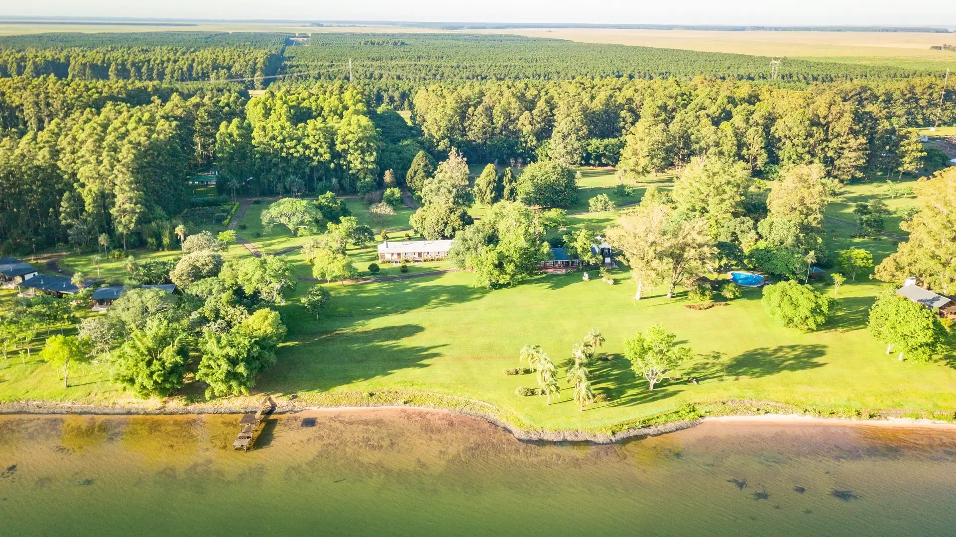 Vista aérea de la estancia sobre la barranca del Paraná, con el parque, el muelle y la forestación detrás