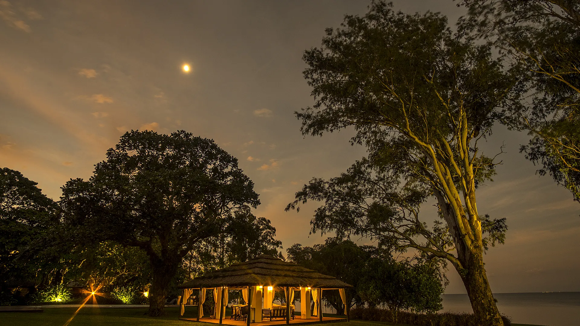 La palapa sobre la barranca del Paraná, encendida bajo la luna, con el río al fondo
